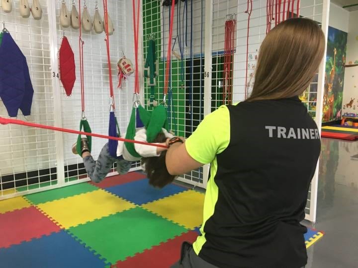 A woman is training a child in a gym.