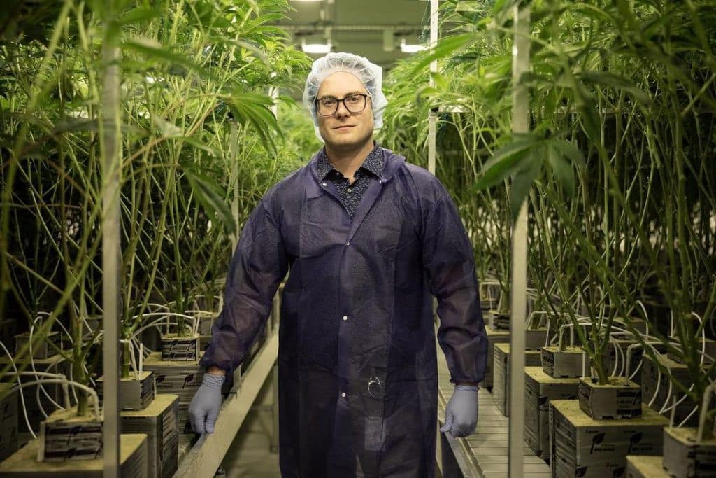 A man in a lab coat standing in front of plants.