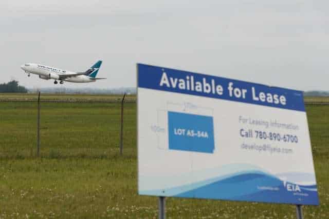 A plane is flying over a sign that says available for lease.