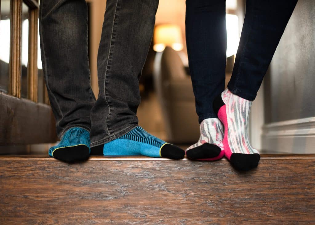 A man and woman standing on stairs wearing colorful socks.