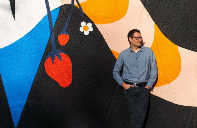 A man standing in front of a colorful mural.