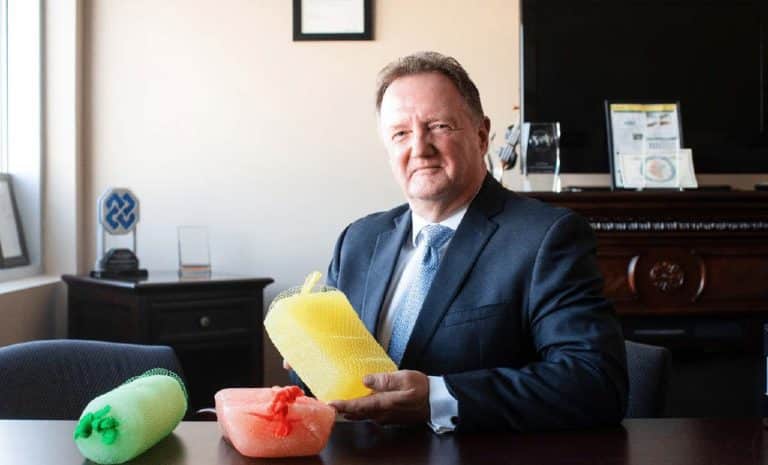 A man in a suit sits at a desk with a bunch of plastic cups.