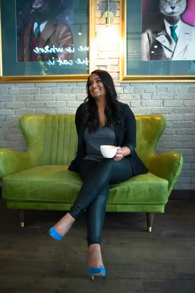 A woman sitting on a green couch with a cup of coffee.