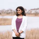 A woman standing in front of a lake.