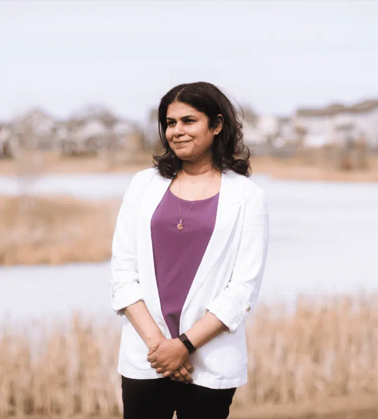 A woman standing in front of a lake.