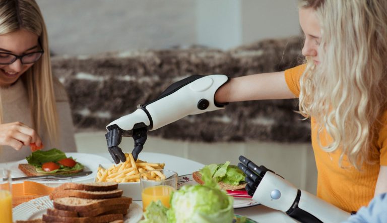 A woman is eating a meal with a robotic arm.