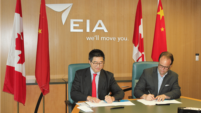 Two men sitting at a table signing a document.