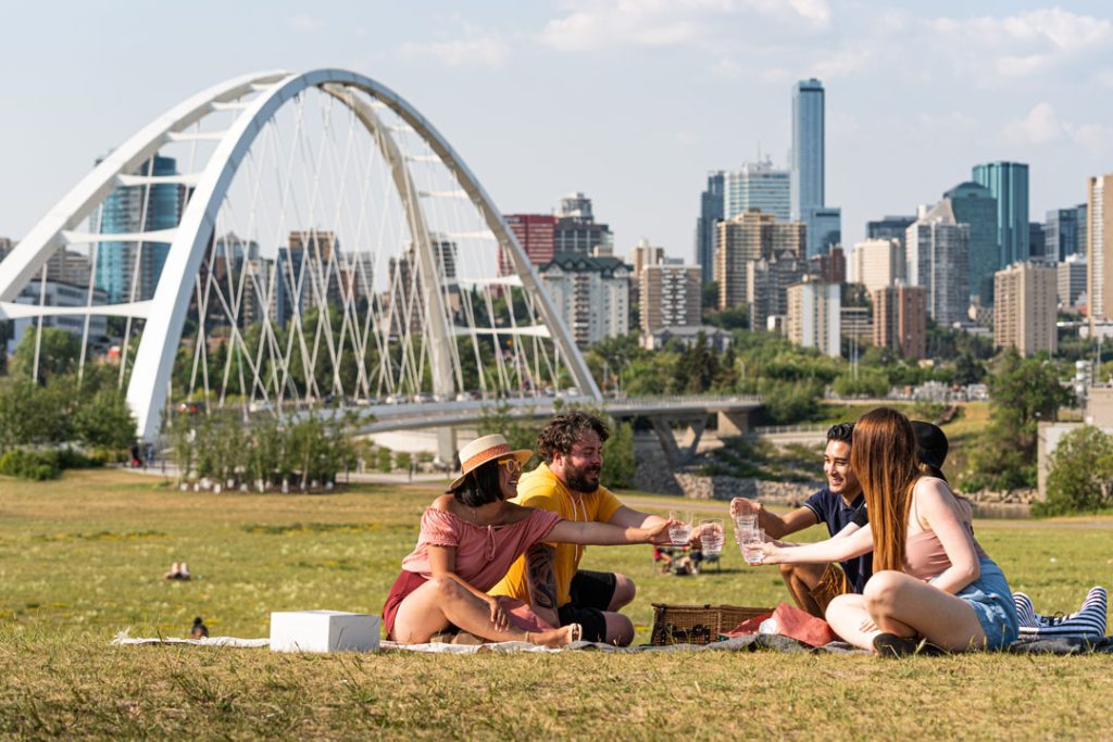 A group of people enjoying a picnic in the park with the calgary skyline in the background.