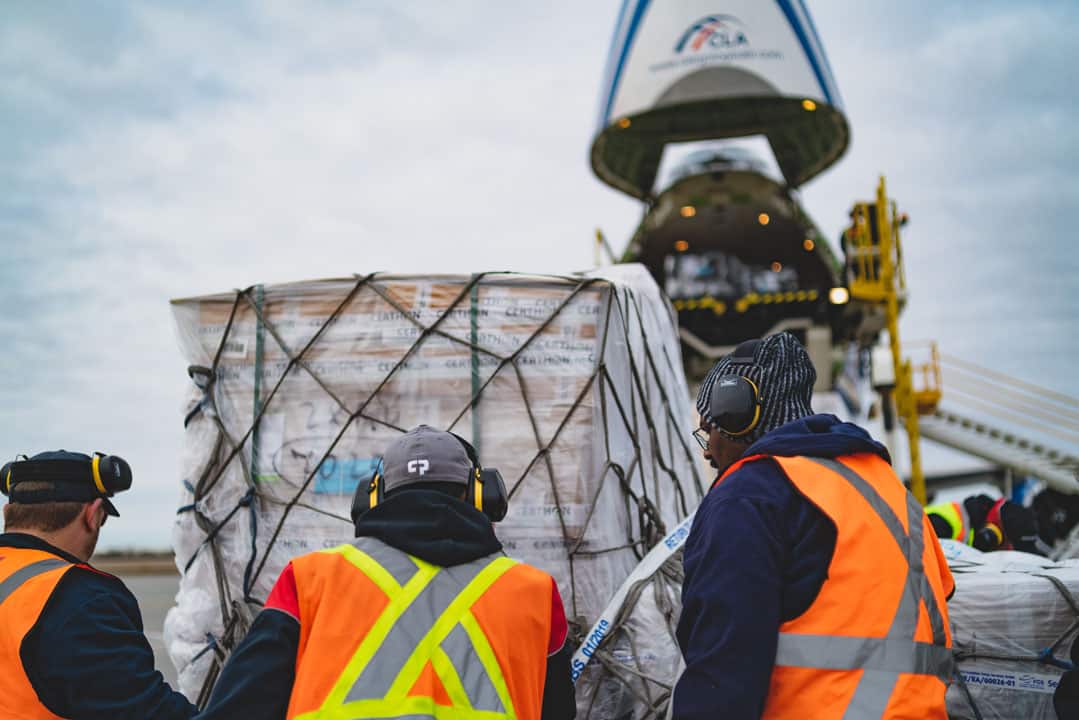 A group of workers loading a plane with cargo.