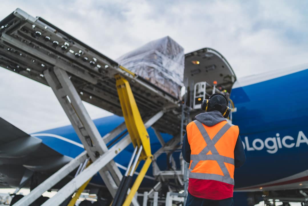 A worker loading boxes onto a large airplane.