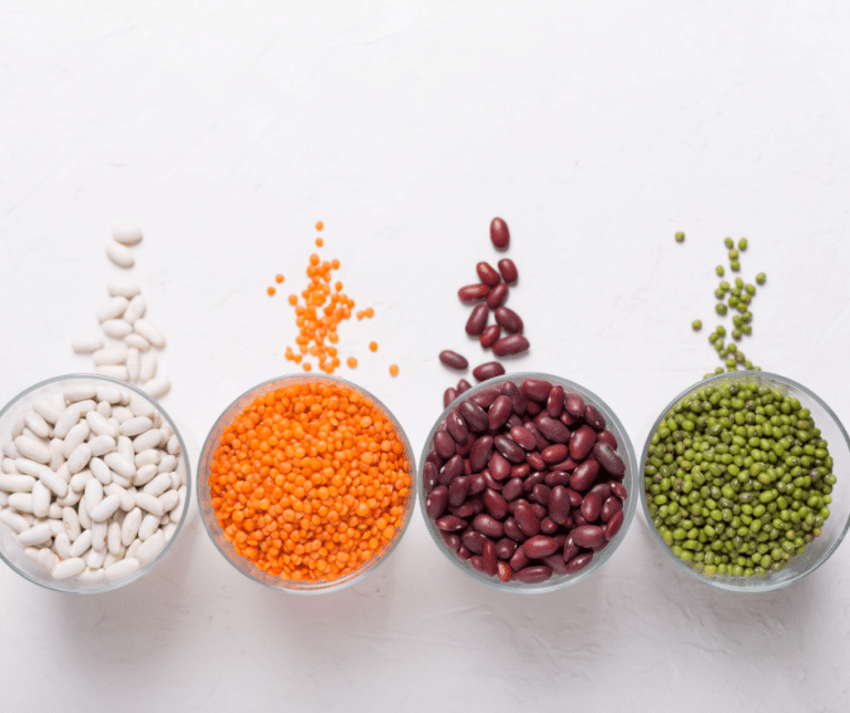 Four bowls of different colored beans and peas on a white background.