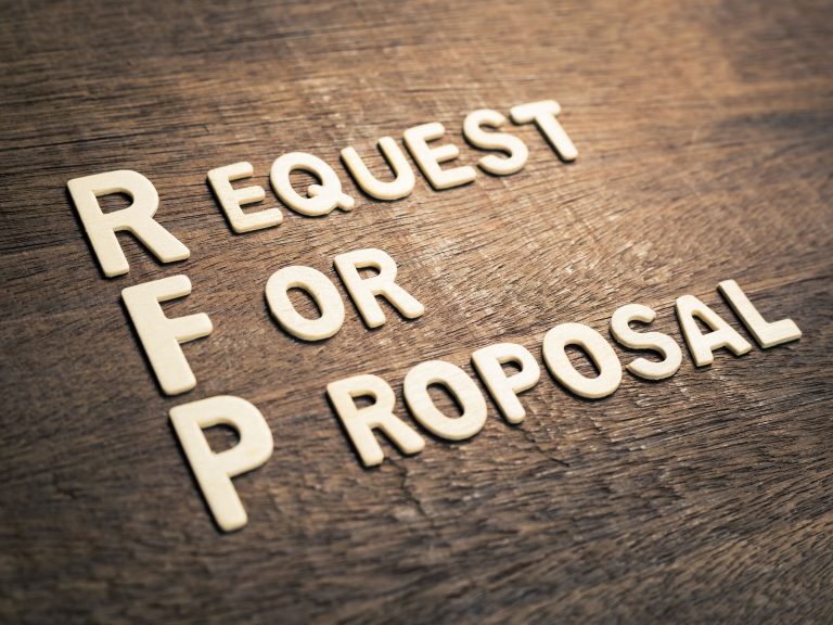 The word request for proposal on a wooden table.