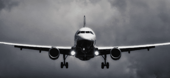 A black and white image of a plane flying in the sky.