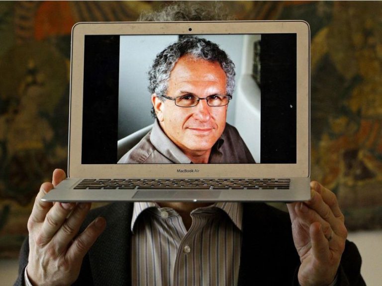 A man holding up a laptop with a picture of a man on it.