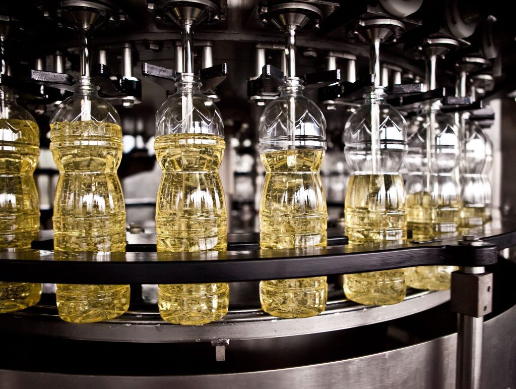 A machine is filling bottles of oil in a factory.
