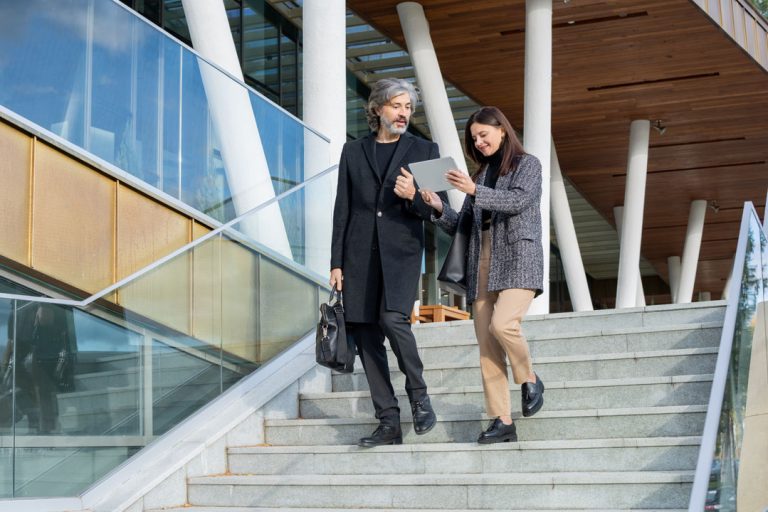 A man and woman are walking down the stairs of an office building.