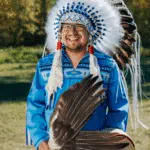 A man wearing a blue and white feathered headdress.