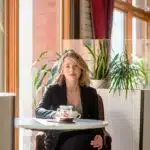 A woman sitting at a table with a cup of coffee.