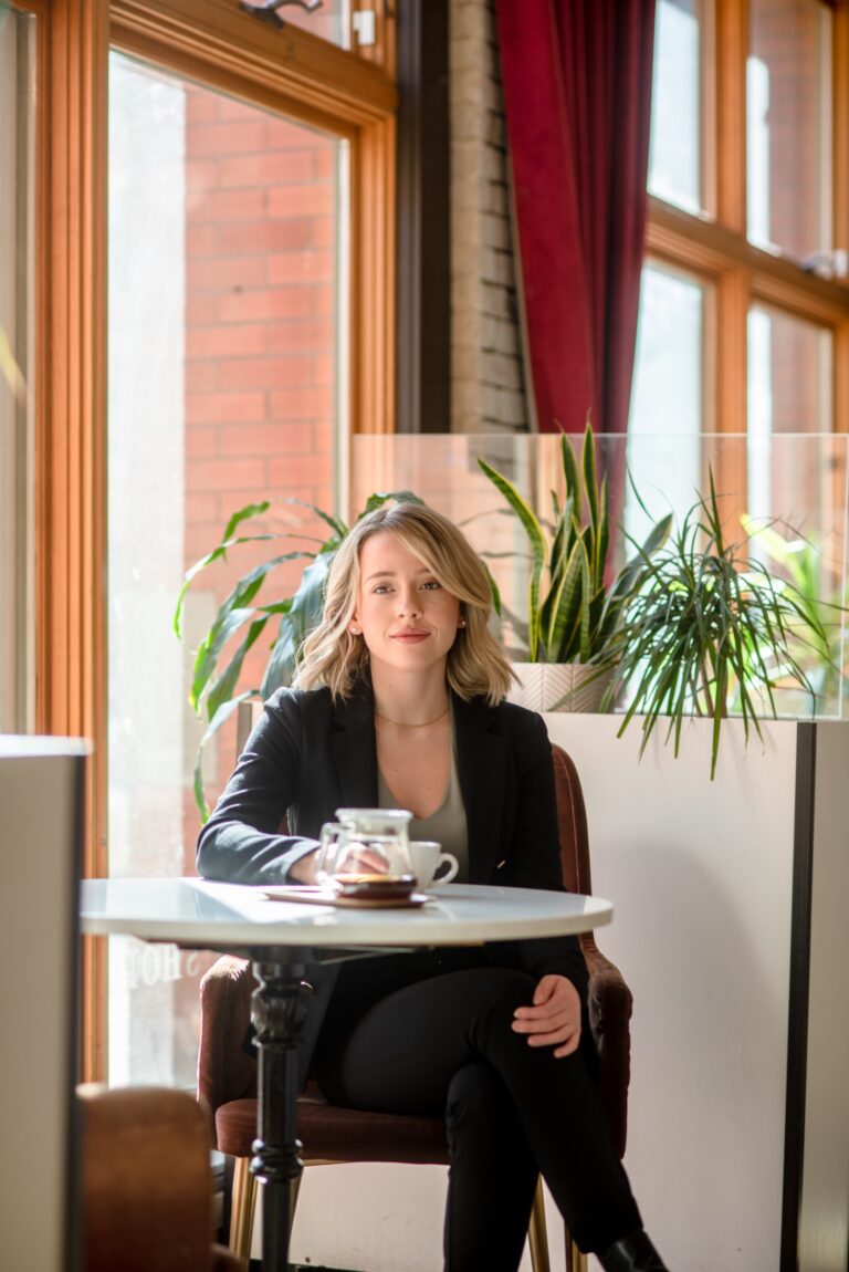 A woman sitting at a table with a cup of coffee.