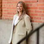 A woman leaning against a brick wall.